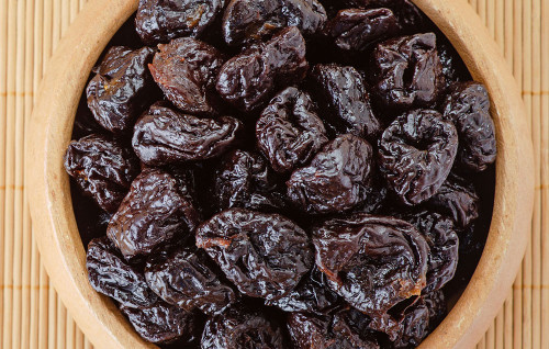 Dried prunes in wooden bowl